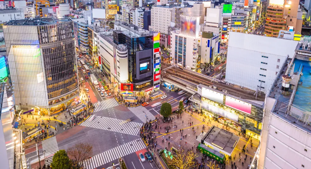 Aerial view of Shibuya Crossing with crowds, traffic, and surrounding buildings in Tokyo